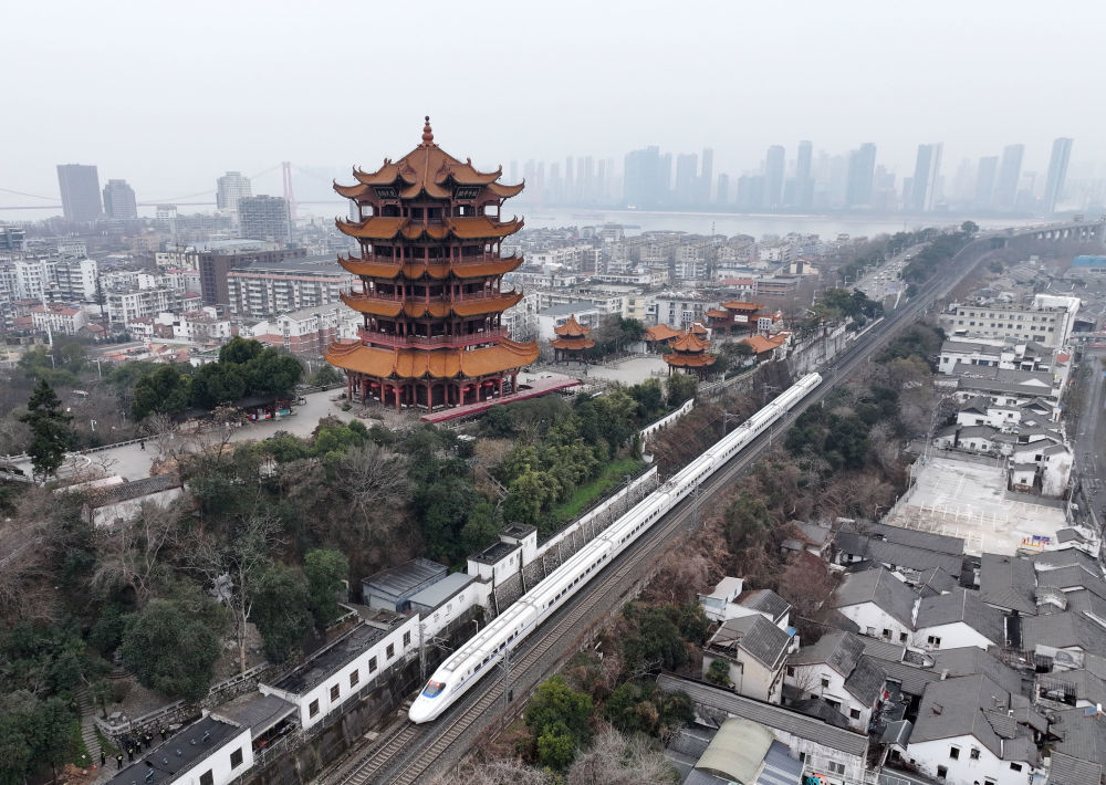 ↑ 1月25日,一列动车组列车经过湖北省武汉市黄鹤楼景区(无人机照片)。新华社发(赵军 摄)