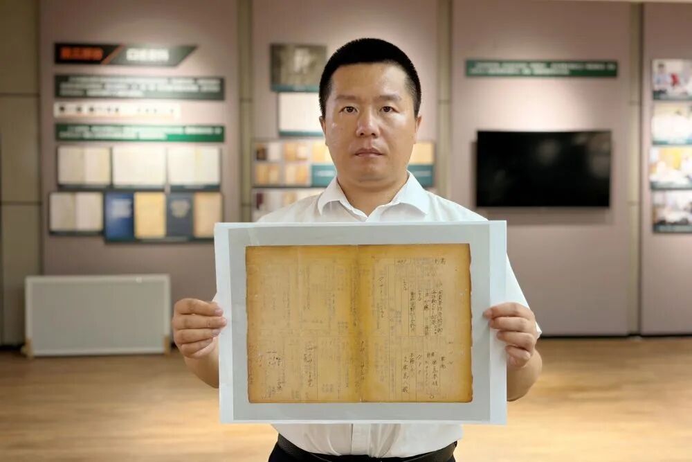 侵华日军第七三一部队罪证陈列馆研究人员金士成展示731部队海拉尔支队《身上申告书》影印件。（受访者供图）