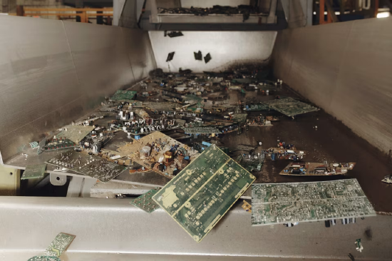 传送带上的电子垃圾,含电路板及其他零部件。回收中心内正在分拣的电子垃圾。