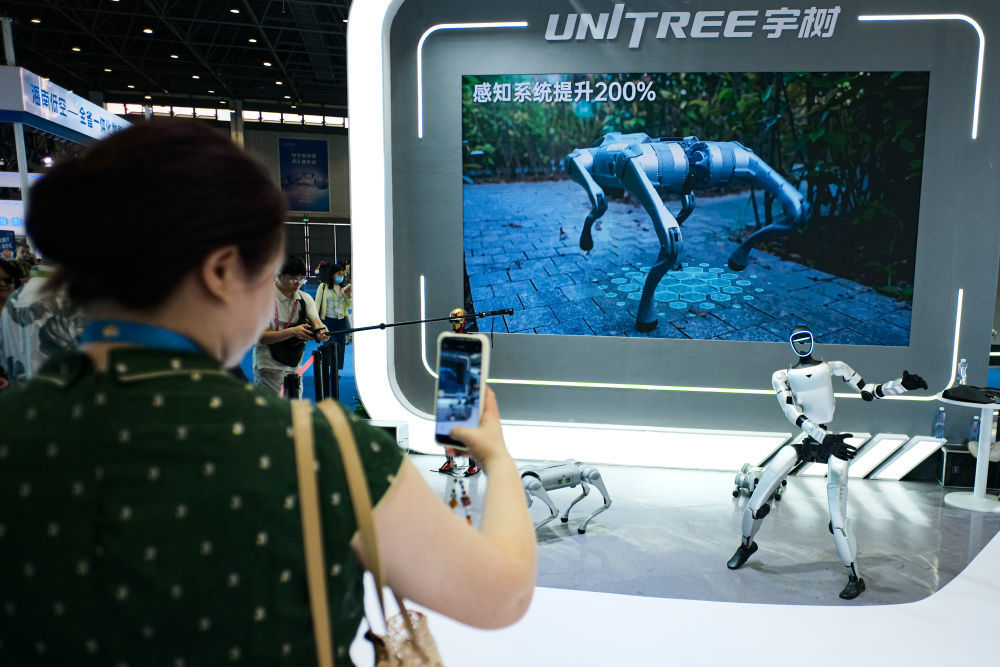 ↑ 4月14日，观众在第六届消博会展厅内拍摄跳舞表演的宇树机器人。新华社记者 辛悦卫 摄