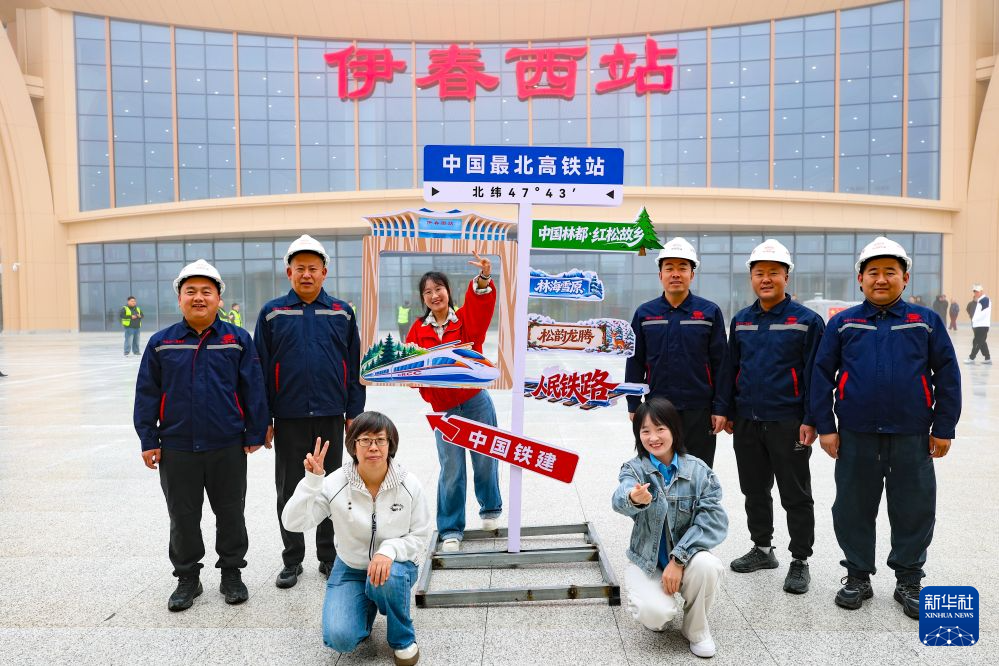9月28日,哈伊高铁建设人员与游客在伊春西站站前广场合影。新华社记者 王松 摄