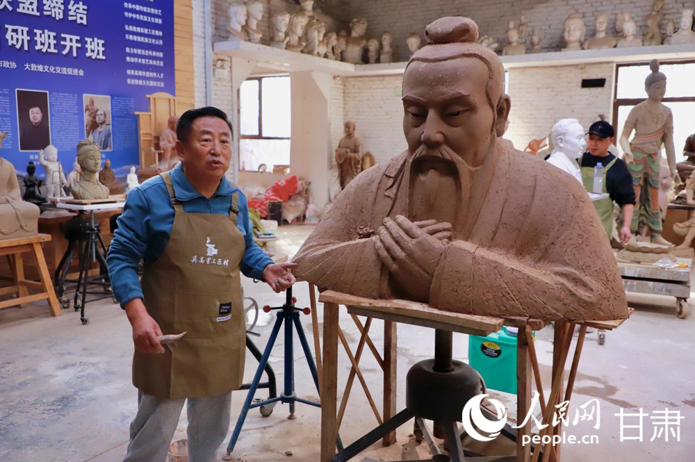 杜永卫在泥塑作品旁介绍敦煌彩塑制作技艺。人民网记者 焦隆摄