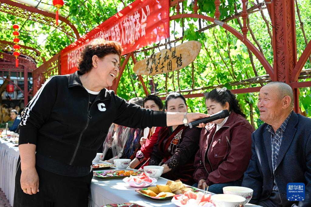 在新疆伊宁县喀拉亚尕奇乡喀拉亚尕奇村“伊犁人的奶茶会”上，乡便民服务中心卫教妇幼岗干部热依兰&middot;艾合买提（左）与村民互动，倡导大家摒弃高额彩礼陋习，弘扬文明新风（5月14日摄）。