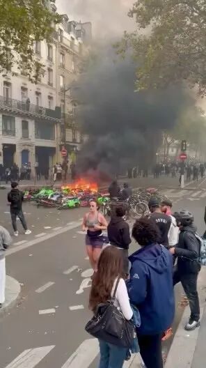 在巴黎街头,一名女子慢跑穿过烟雾弥漫的街道,无视周围的骚乱。图源:美媒
