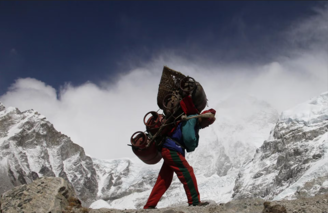 一名背夫背着行李从珠峰大本营出发,这样辛苦的工作通常由夏尔巴人承担