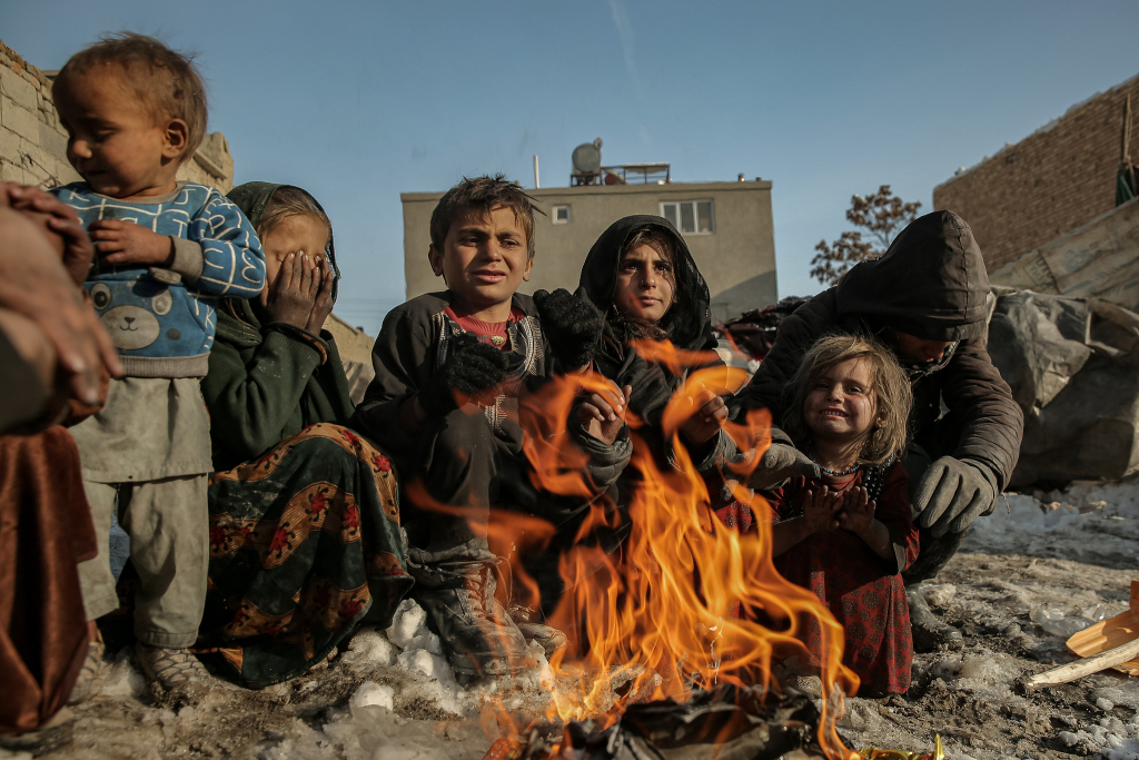 当地时间2026年2月3日,阿富汗喀布尔,流离失所家庭的人们在临时避难所外围坐在火堆旁取暖。援助组织和联合国机构报告称,数百万阿富汗难民从巴基斯坦及周边国家返回,仅2025年就有280万人,这加剧了人道主义压力,并产生了冬季期间对庇护所、食物和保护的迫切需求。视觉中国 图