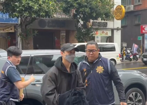 邱胜翊（中）4月1日上午因涉“闪兵案”被警方拘提到案。图源：台媒