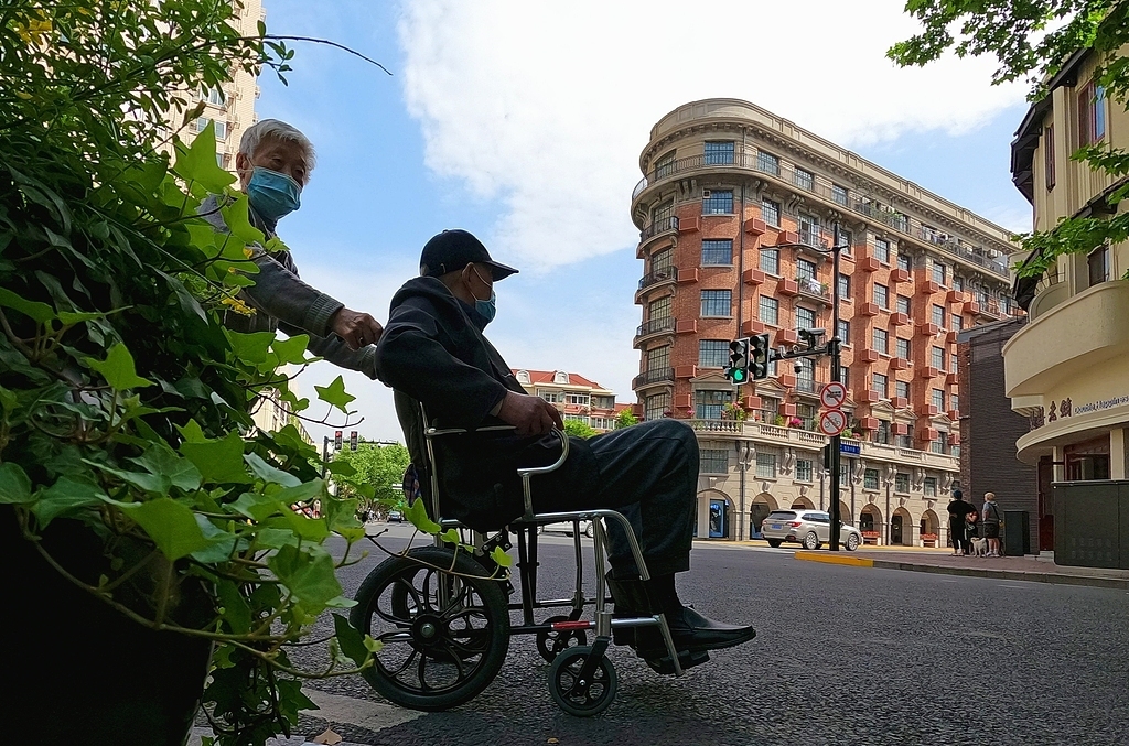 一位老人坐着轮椅路过武康大楼。视觉中国 资料图