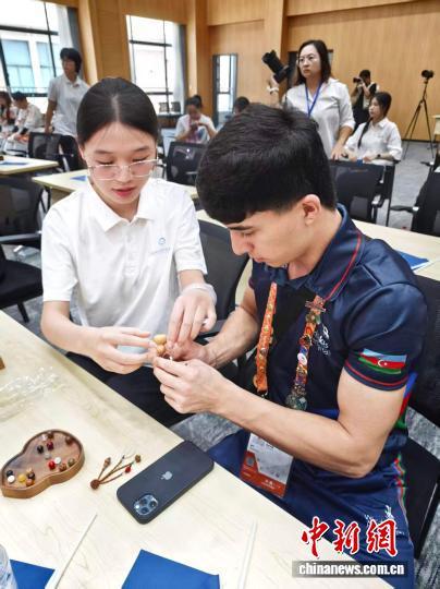 外国友人在志愿者的帮助下制作中式葫芦挂件。 中新网记者 许婧 摄