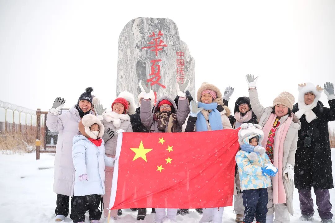 2月15日，游客在位于黑龙江省抚远市的黑瞎子岛景区“华夏东极”地标处与国旗合影。经济日报记者朱双健摄