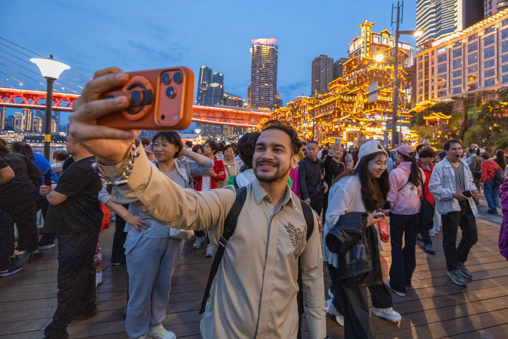 ↑ 4月22日，一名印度游客在重庆市渝中区洪崖洞景区前自拍。