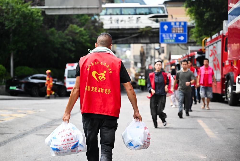 7月19日,志愿者在重庆彭水县山体崩塌救援现场附近提运物资。