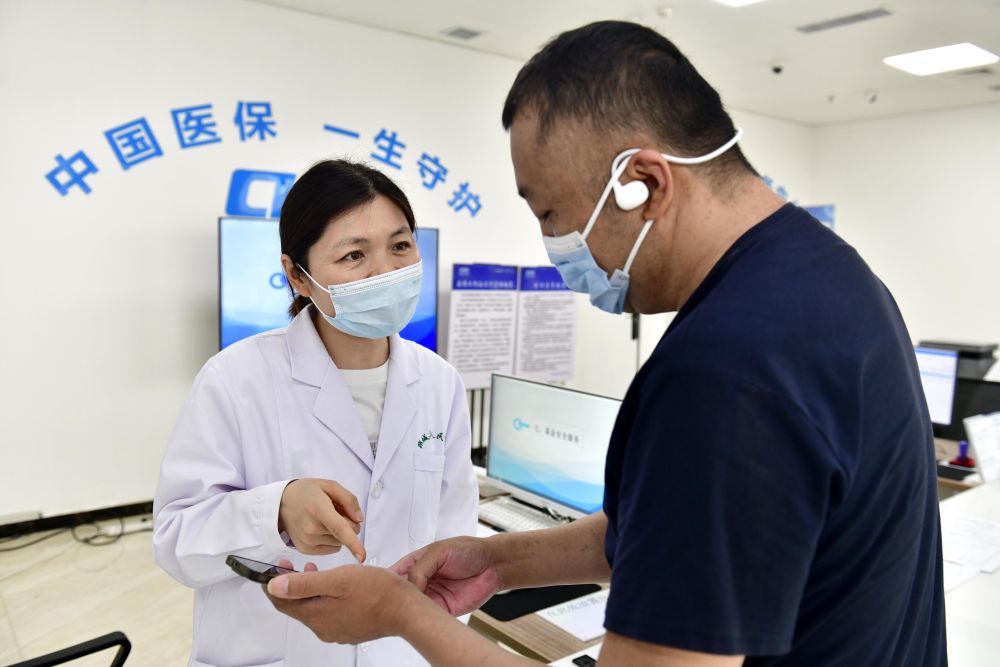 2025年8月21日，在山东省郓城县人民医院医保便民服务站，工作人员帮助居民办理医保业务。新华社记者 郭绪雷 摄