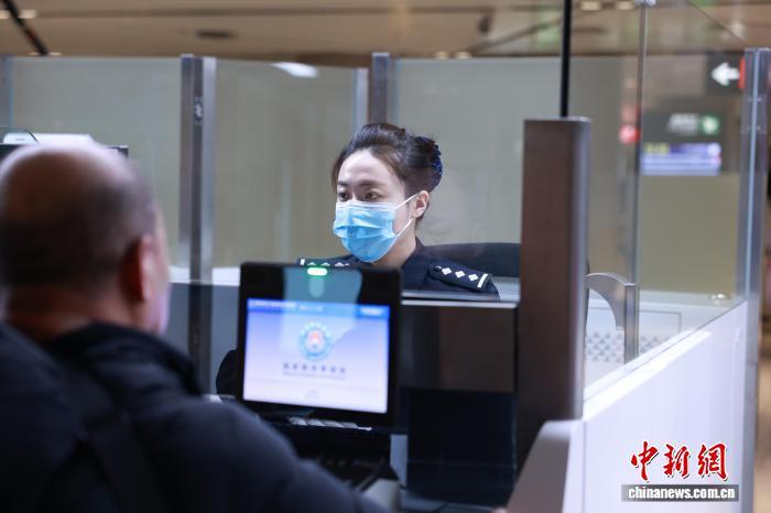 哈尔滨出入境边防检查站移民管理警察为入境旅客办理通关手续。　陈尚楠 摄