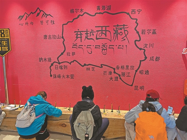图为一排游客坐在印有“穿越西藏”地理标识的红墙前。记者 晓勇 摄