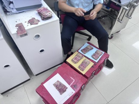 图为工作人员对严重霉变、残缺的人民币进行清分整理