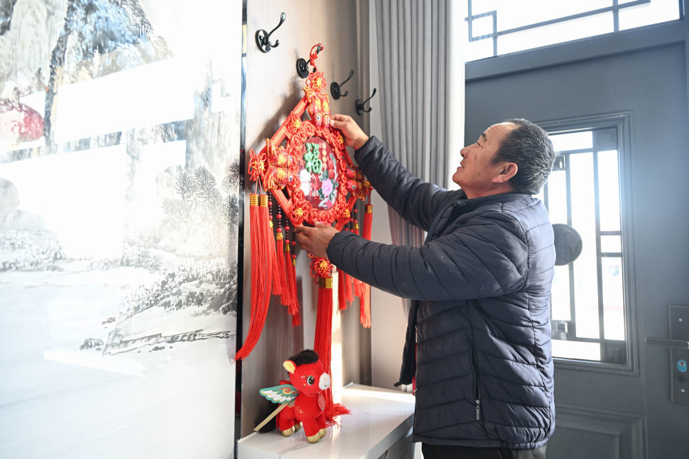土默特右旗双龙镇路三圪堆村村民吕二豹在挂福字。新华社记者贝赫 摄