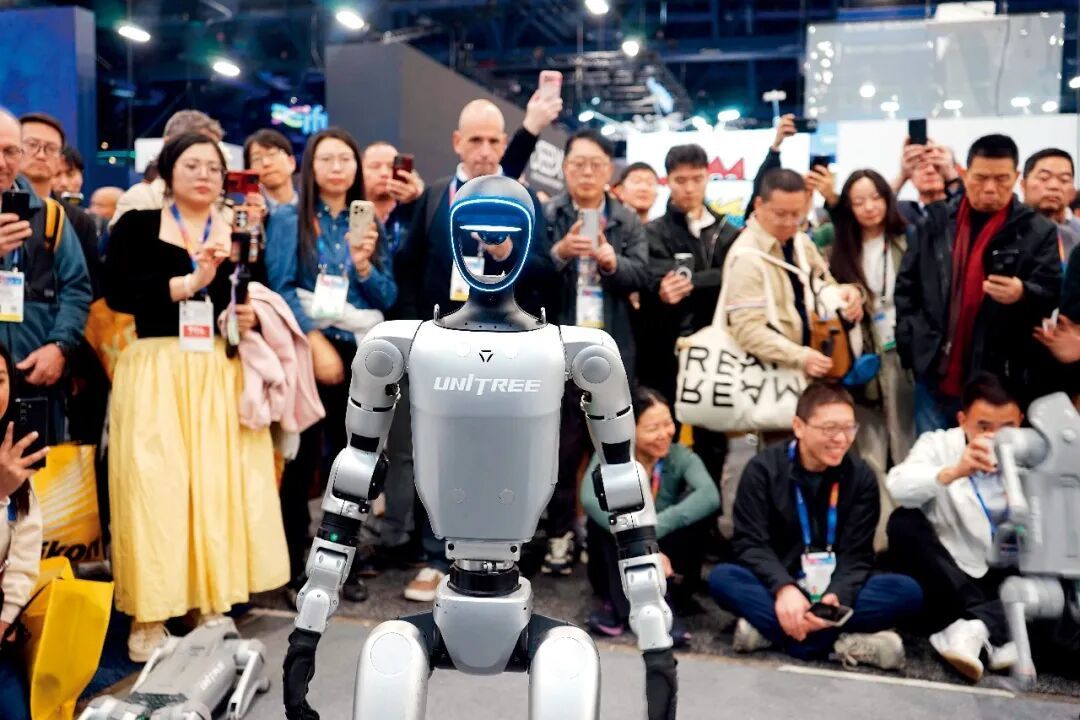 2025年 1月8日,在美国拉斯维加斯消费电子展上,人们在宇树科技展区观看机器人展示。图/新华