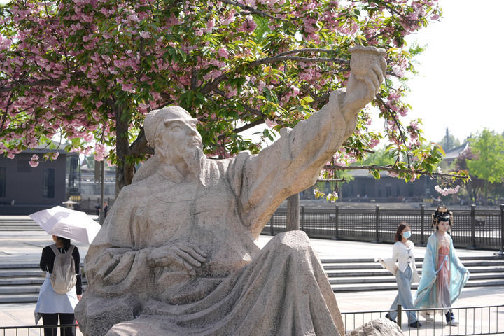 人们在西安市大雁塔北广场上诗人李白造型的雕塑附近游玩(4月9日摄)。新华社记者 邵瑞 摄