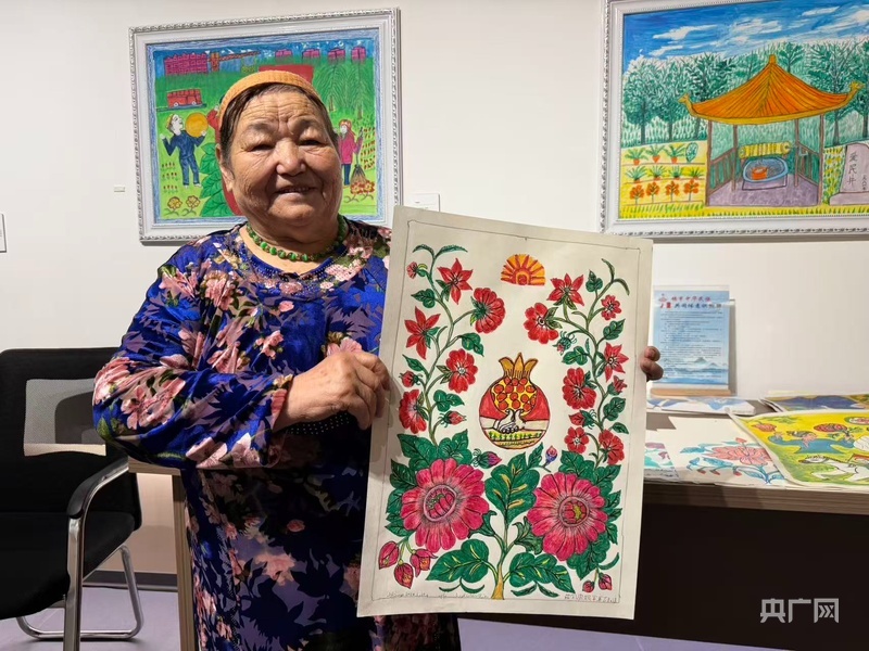 茹则瓦妮罕&middot;库尔班向记者介绍她的画作 （央广网记者 丁安 摄）