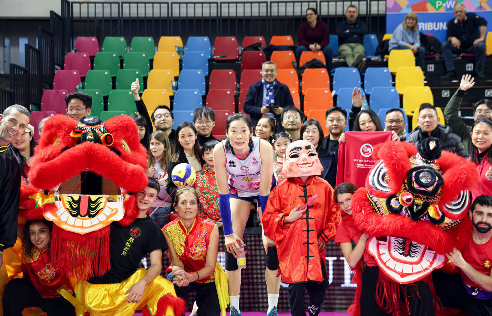 2024年2月4日，在意大利斯坎迪奇，斯坎迪奇队球员朱婷与当地舞龙舞狮表演者和观众在赛后合影。该舞龙舞狮表演队由意大利当地的中国功夫爱好者组成。