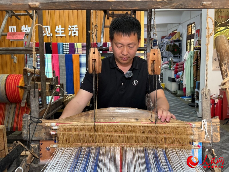 长胜街手作工坊里,陶文成正在织布。人民网记者 周恬摄