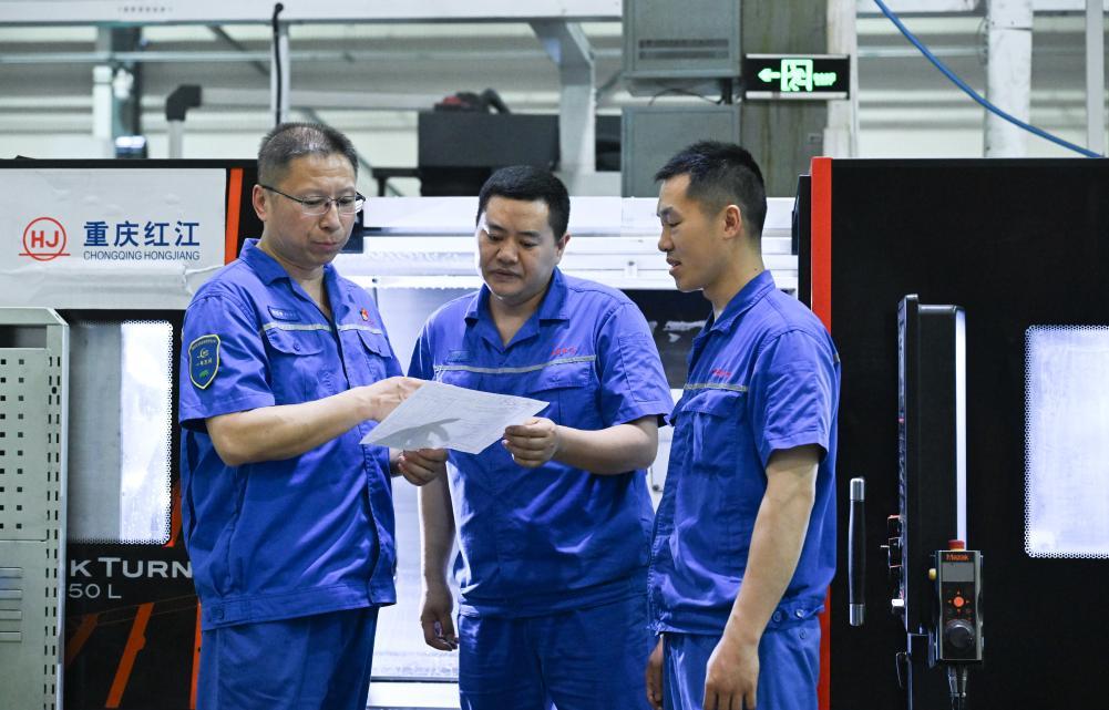 2025年5月23日，傅国涛（左一）在重庆红江机械有限责任公司生产车间与同事交流。新华社记者 王全超 摄