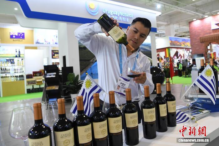 2021年7月9日，第27届中国兰州投资贸易洽谈会展馆内，主宾国乌拉圭展馆的工作人员介绍乌拉圭红酒。中新社记者 杨艳敏 摄