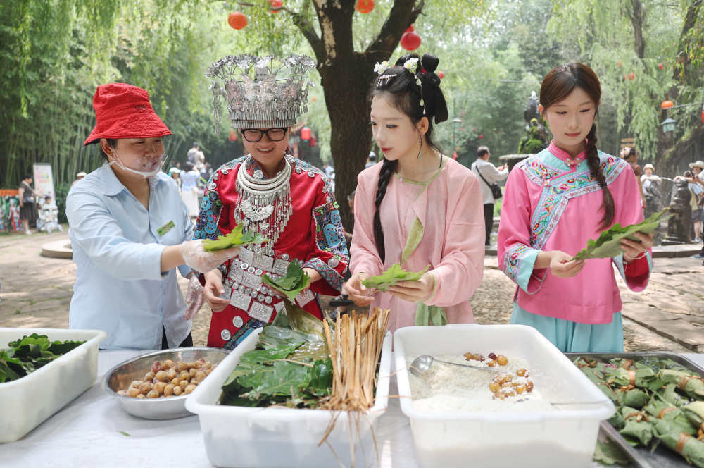 6月20日，在山东省临沂市沂南县铜井镇竹泉村，游客参与包粽子比赛。新华社发（王彦冰摄）