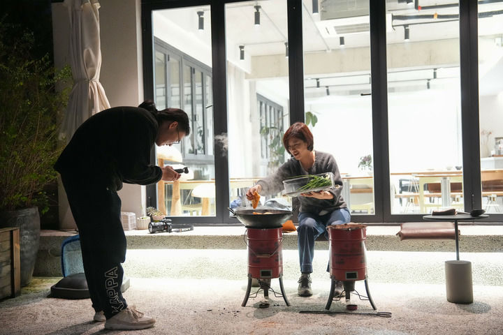 浙江省宁波市奉化区溪口镇东山村民宿主董凤洁(右)在民宿内拍摄炒年糕的短视频(2025年11月13日摄)。新华社记者 黄宗治 摄