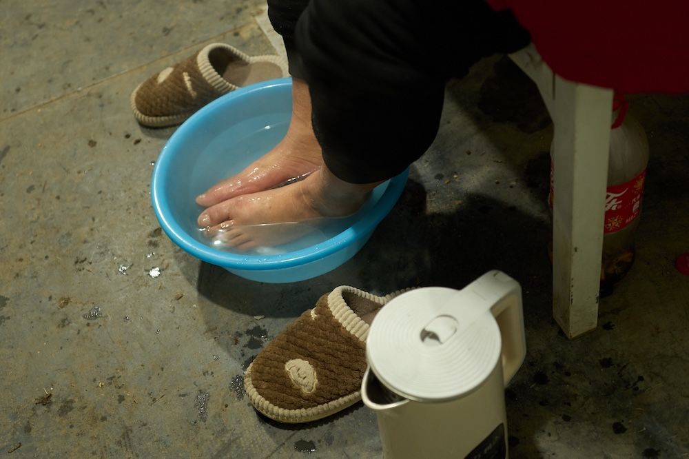 宿舍内，工友用热水烫脚，舒缓身体的疲乏。