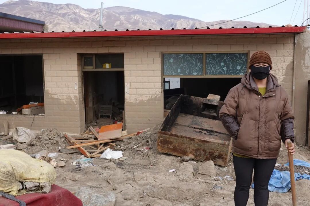 丁亮妻子站在被山洪“袭击”过的旧屋子前