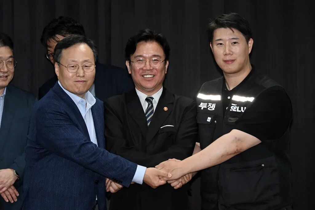 当地时间2026年5月20日，三星电子DS部门人事组长与三星集团初创企业工会三星电子支部委员长崔胜浩签署临时协议，随后与雇佣劳动部部长金英勋合影留念。图/视觉中国