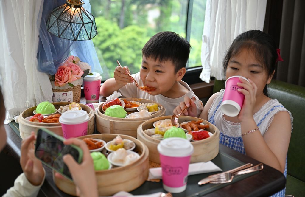 7月5日,游客在“老爸茶·海口巴士”上品尝茶点。新华社记者 郭程 摄