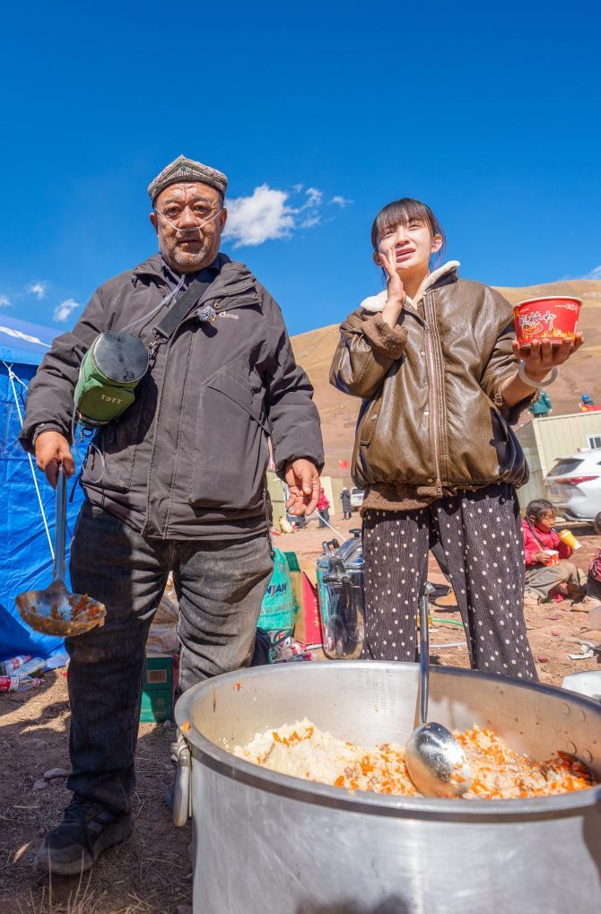 10月26日,在巴青县玛如乡扎若改村,阿里木江·哈力克(左)和折佳欣给群众盛抓饭。