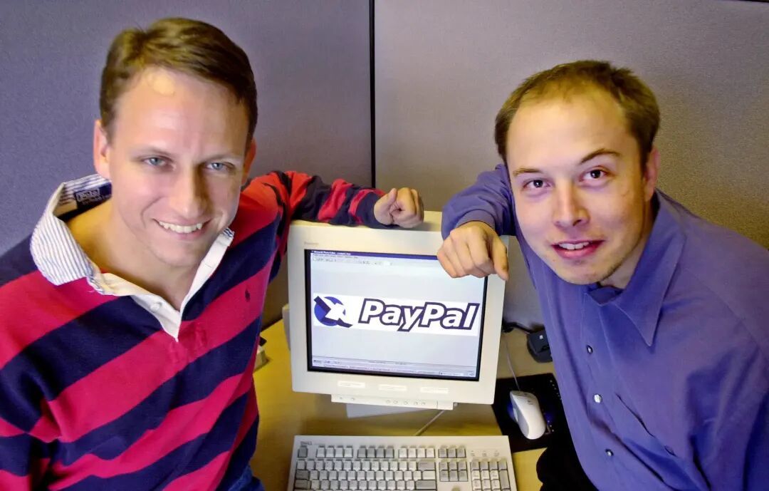 ·2000年，彼得·蒂尔（左）与马斯克（右）在PayPal公司标识旁合影。（盖蒂图片社）