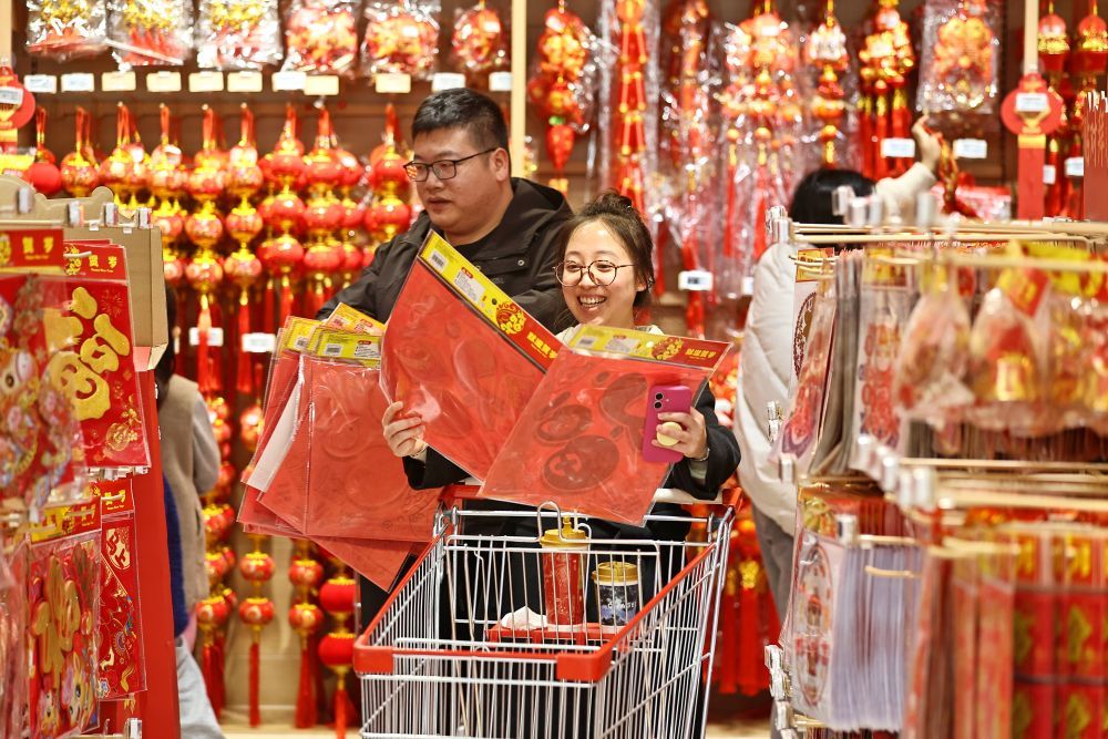 ↑ 2月14日，在浙江省嘉兴市南湖区一家大型商场“年货一条街”，市民在选购福字。新华社发（金鹏 摄）