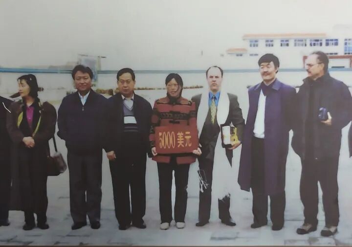 这是“赛考斯”(右三)与殷玉珍(中)于2000年春在捐赠仪式上的合影(资料照片)。