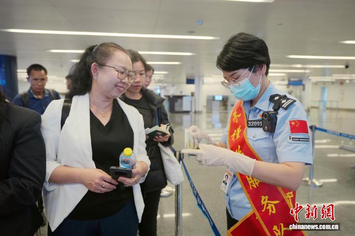 图为南宁边检站“朱槿花服务队”在南宁机场入境大厅为参展客商提供政策解答。梁箫 摄