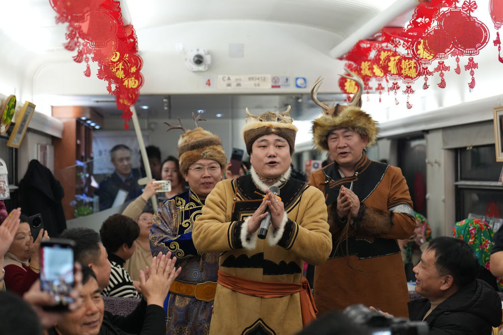2025年1月11日，鄂伦春族民歌赞达仁传承人古拉依尔恩特（中）在黑龙江开行的2025年首趟民族非遗文化列车K7041上演唱。列车从哈尔滨开往漠河，鄂伦春族非遗文化传承人在车上展示桦树皮画、面塑、刺绣等非遗项目。在冰雪旅游季节，民族非遗文化列车让旅客们在车上近距离体验非遗文化，更好满足了旅客多元化的出行需求。