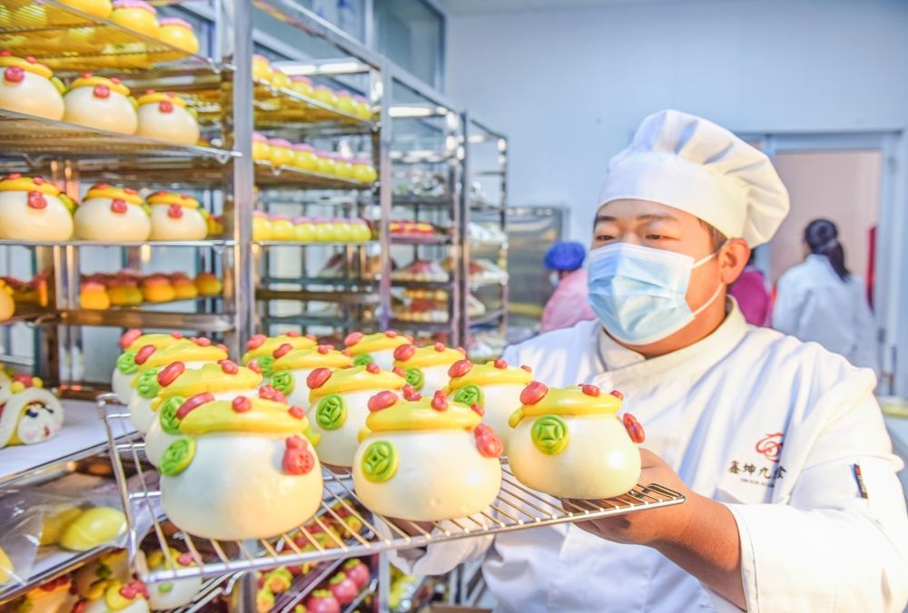 ↑1月13日,在山东省胶州市九龙街道,黑氏传统花馍非遗工坊店主黑尤坤将花馍从货架上取下。新华社发(王昭脉摄)