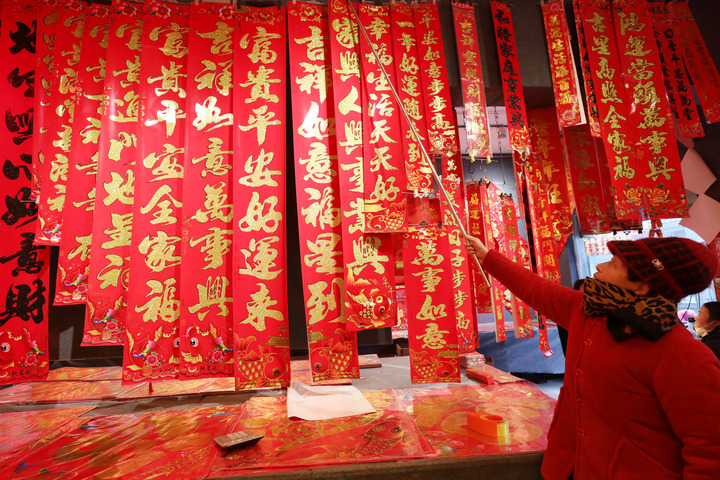 2022年1月25日，当日是农历小年，河南省焦作市温县赵堡镇赵堡村年货市场一家店铺的店主在整理春联。新华社发（徐宏星 摄）