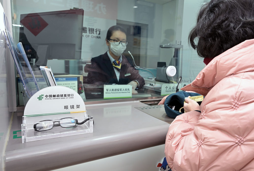 2月10日，在北京西城区中国邮政储蓄银行新街口支行，工作人员在辅助老年人办理个人业务。该行根据周边老龄人口多的特点，灵活开展柜员服务、设置辅助应急用品等便民举措。