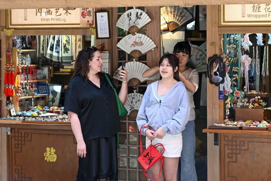 5月5日,外国游客在上海豫园商城内体验佩戴缠花发饰。新华社记者陈浩明摄