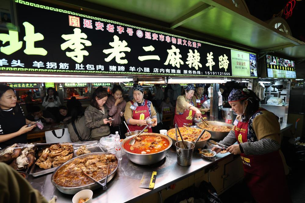 9月15日,游客在延安二道街夜市品尝陕北特色美食。