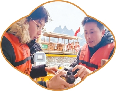 广西漓江景区，筏工（右）在向游客介绍电动排筏。　　本报记者 张云河摄