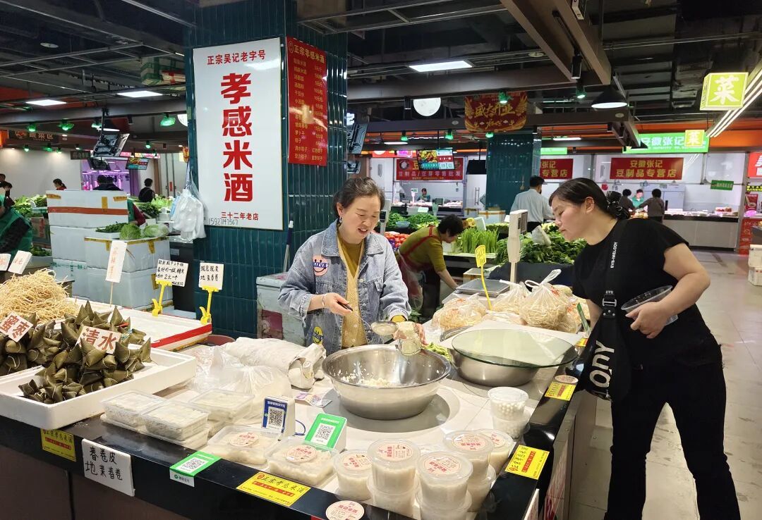 武汉地铁洪山广场站内开设的鲜生市集上,市民在选购孝感米酒。(图/视觉中国)