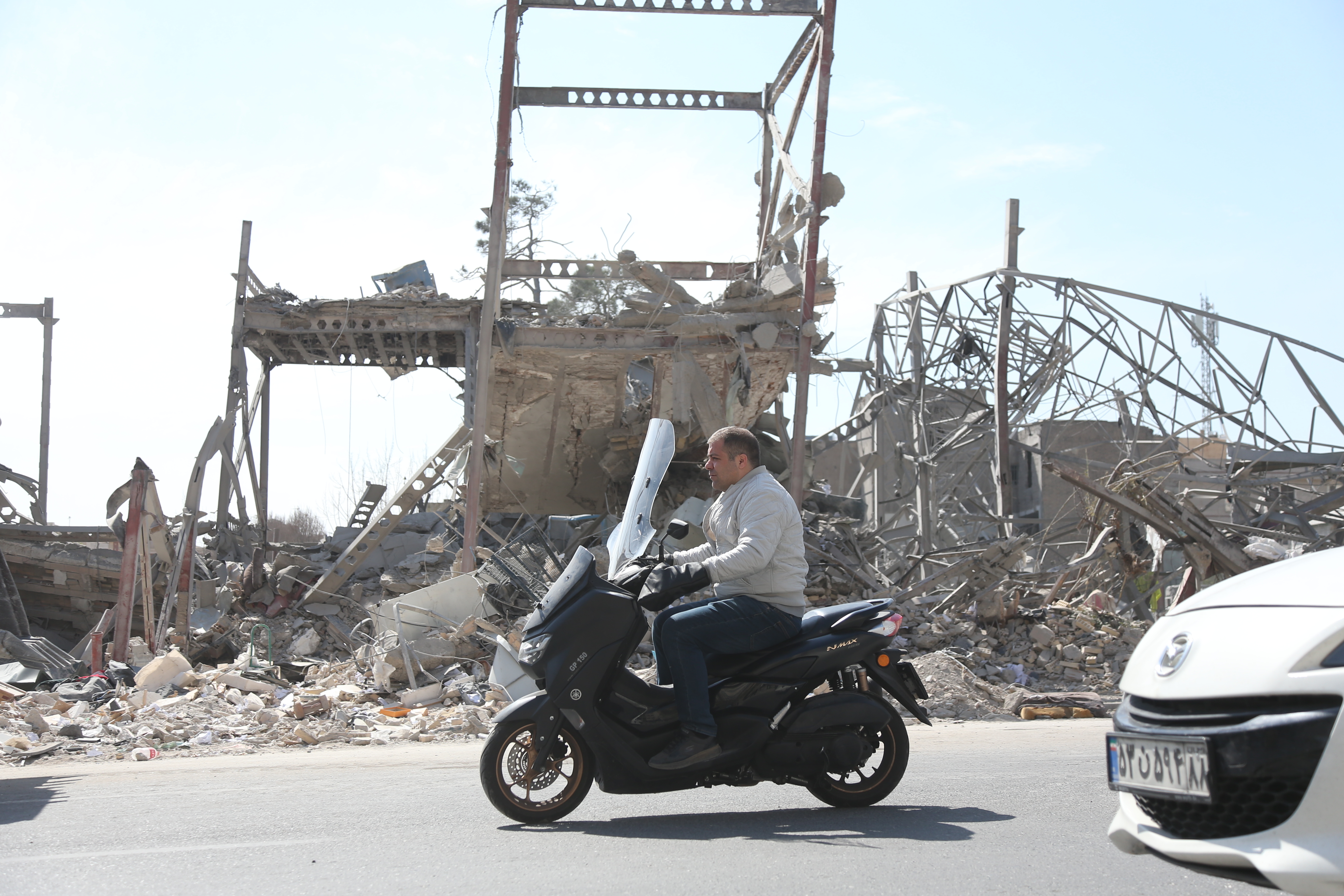 3月4日，在伊朗首都德黑兰，一名男子骑车驶过建筑废墟。新华社记者沙达提摄