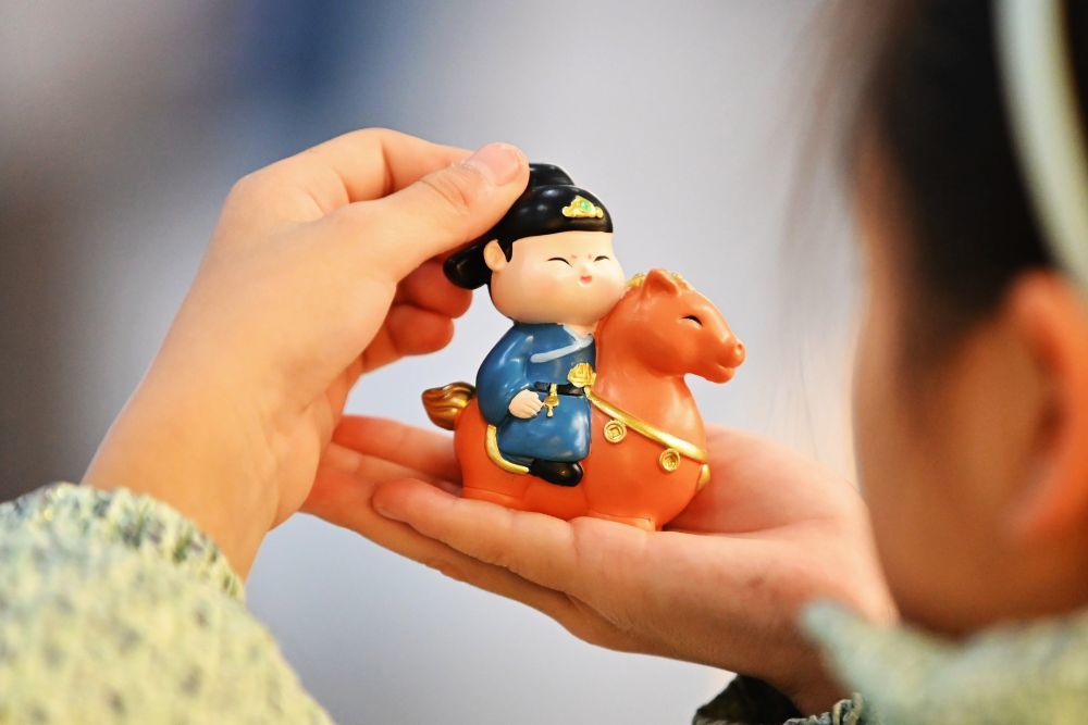 1月17日，在山东滕州博物馆文创商店，一名小朋友选购“踏马游春”文创摆件。新华社发（李志军 摄）