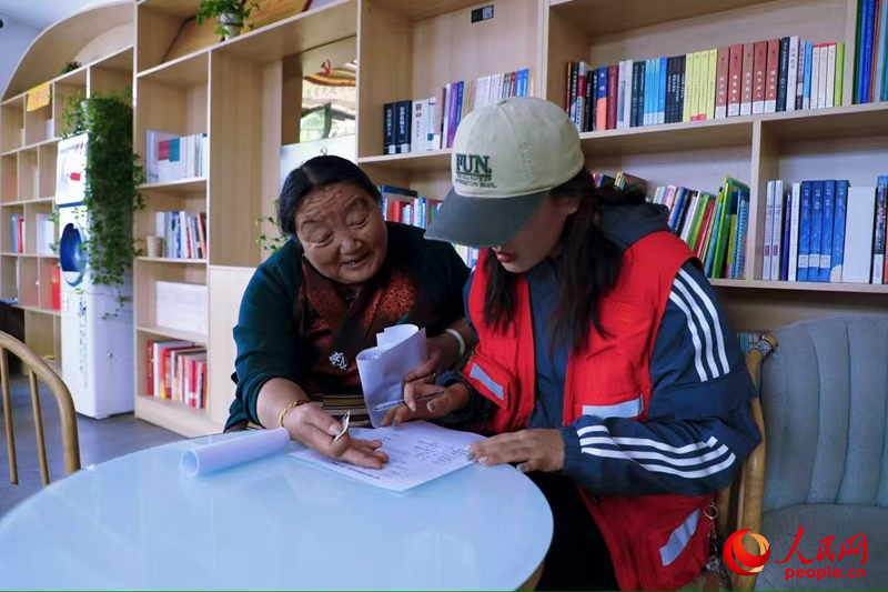 拉萨市幸福社区的网格员协助老人填写双联户档案表。人民网记者 次仁罗布摄